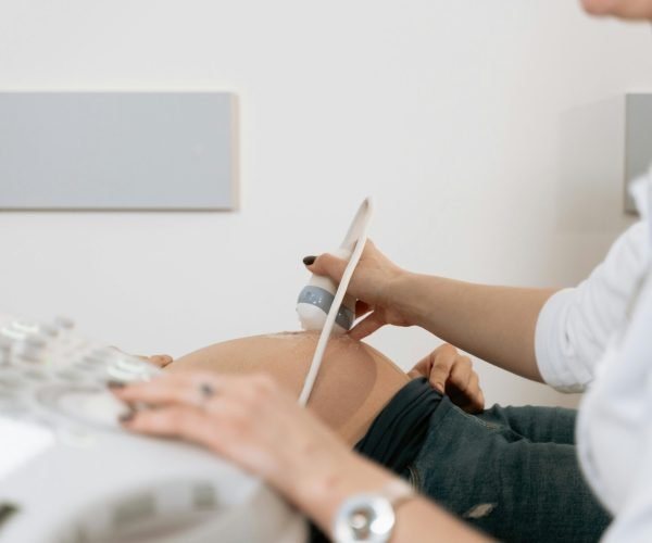 A healthcare professional performs an ultrasound on a pregnant woman in a clinic.